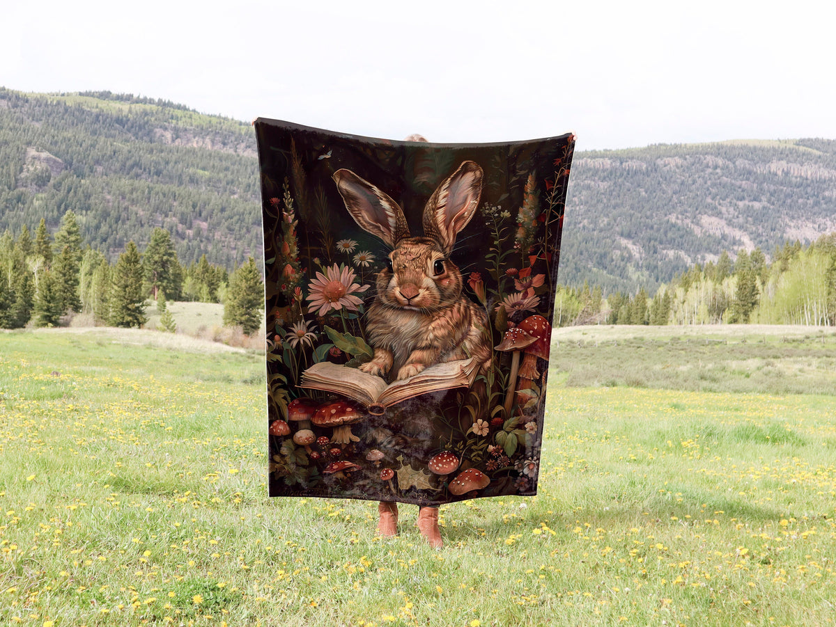 a blanket with a picture of a rabbit reading a book