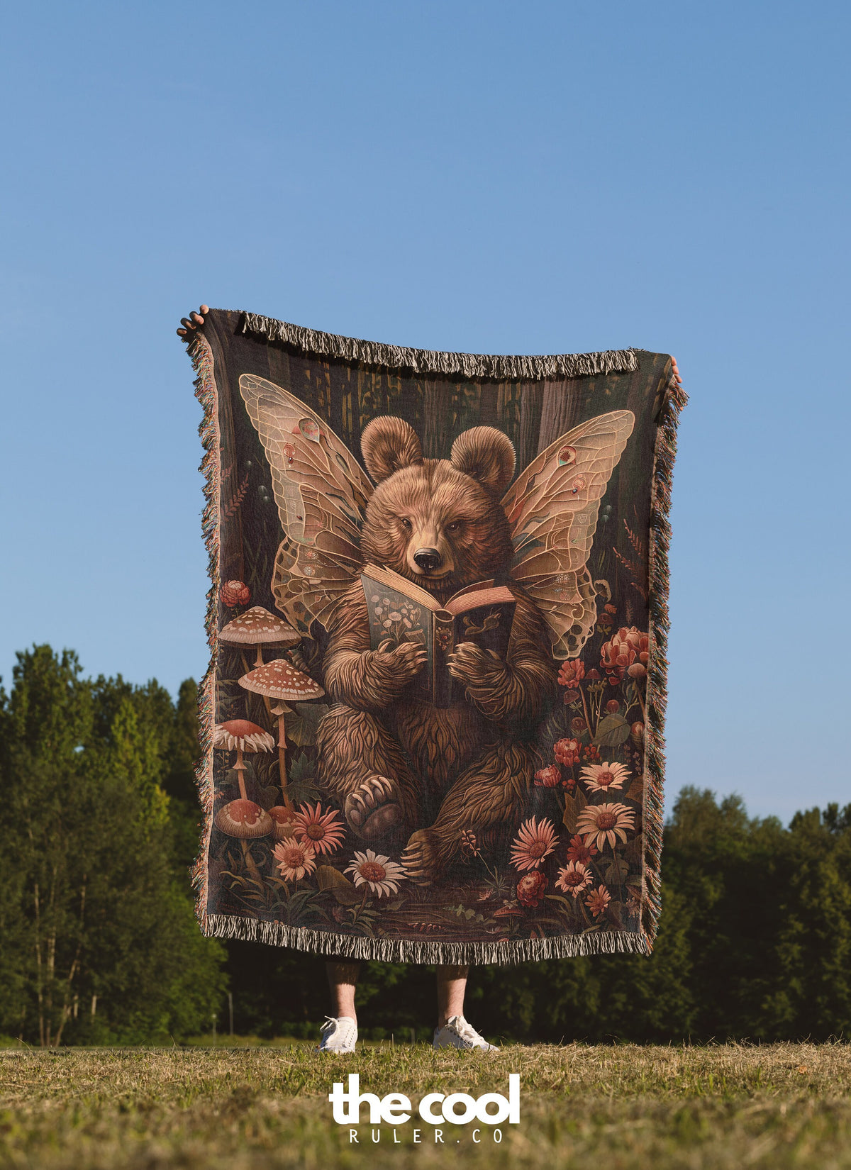 a woman standing in a field holding a bear tapestry