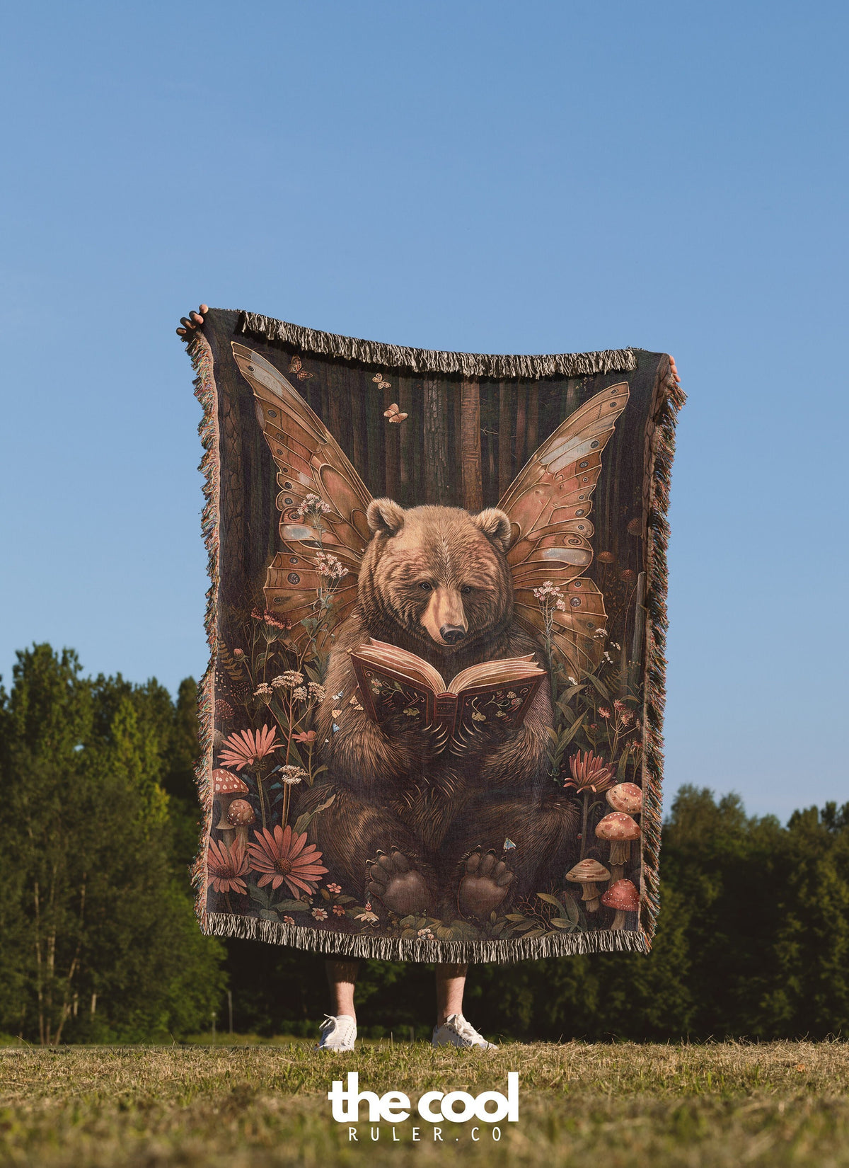 a woman standing in a field holding a bear tapestry