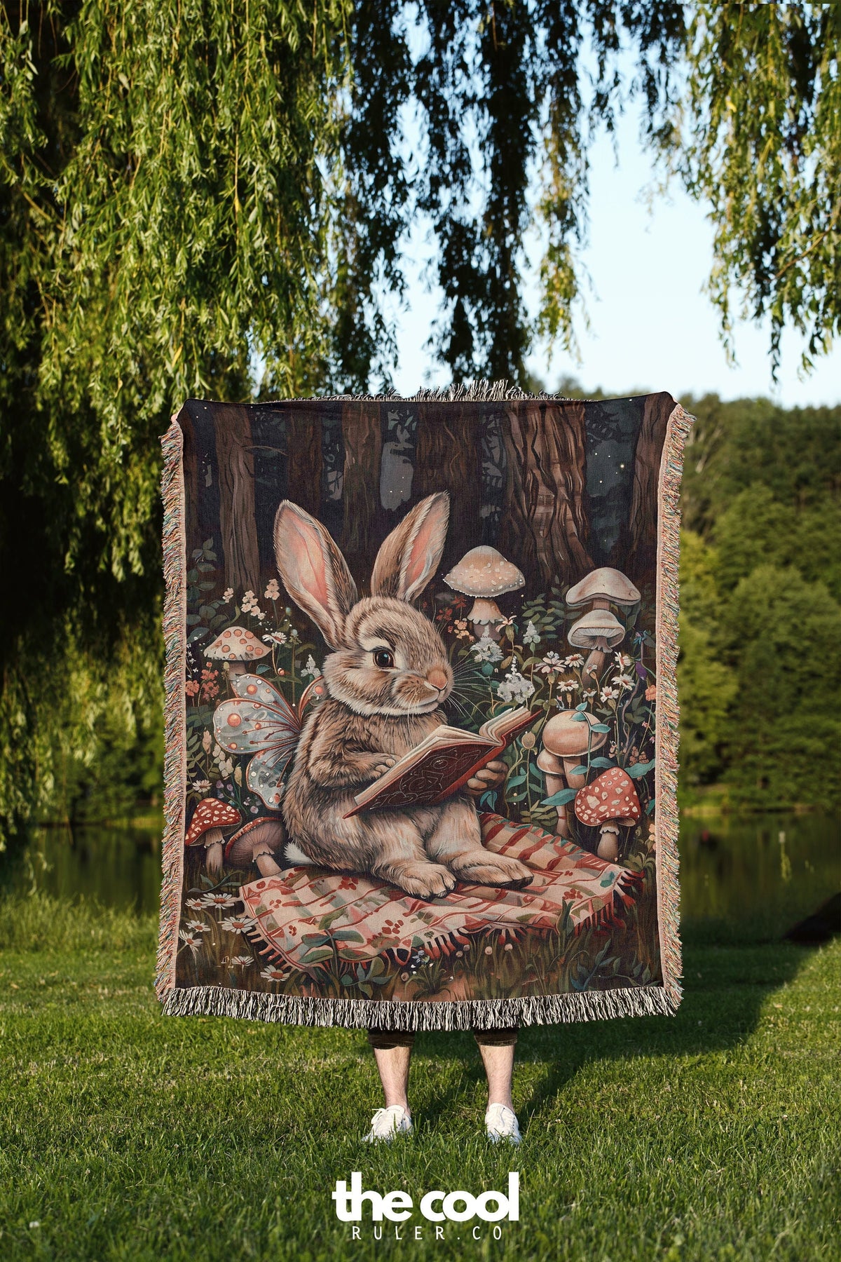 a woman standing in the grass holding a blanket with a picture of a rabbit reading