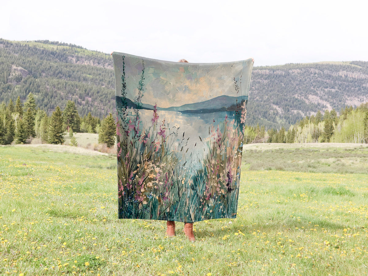 a woman is holding a painting in a field