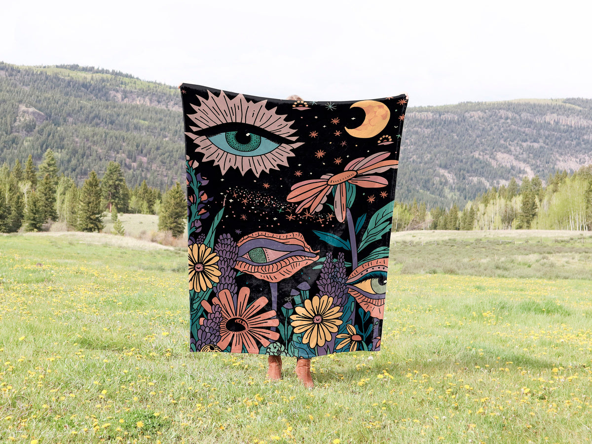 a woman standing in a field holding a blanket