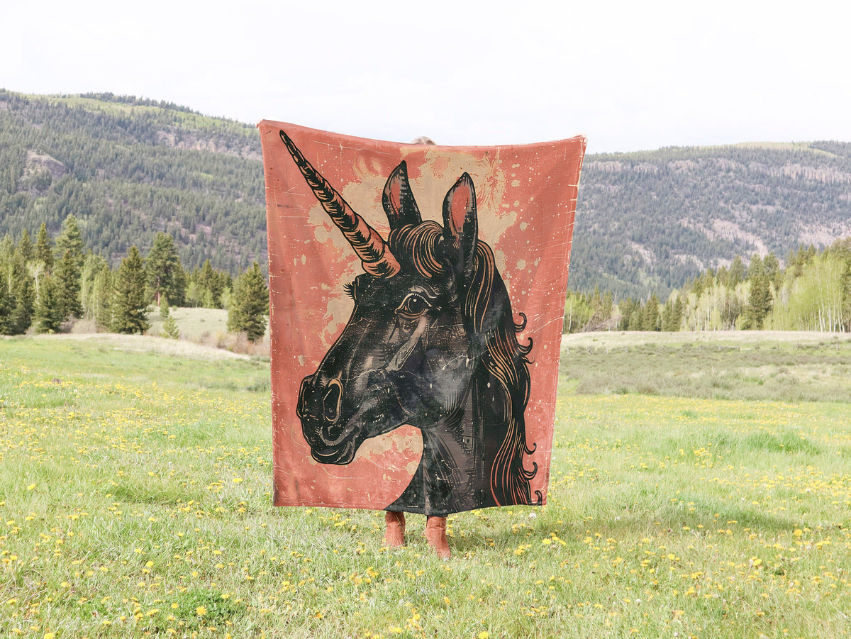 a black horse with a long horn standing in a field