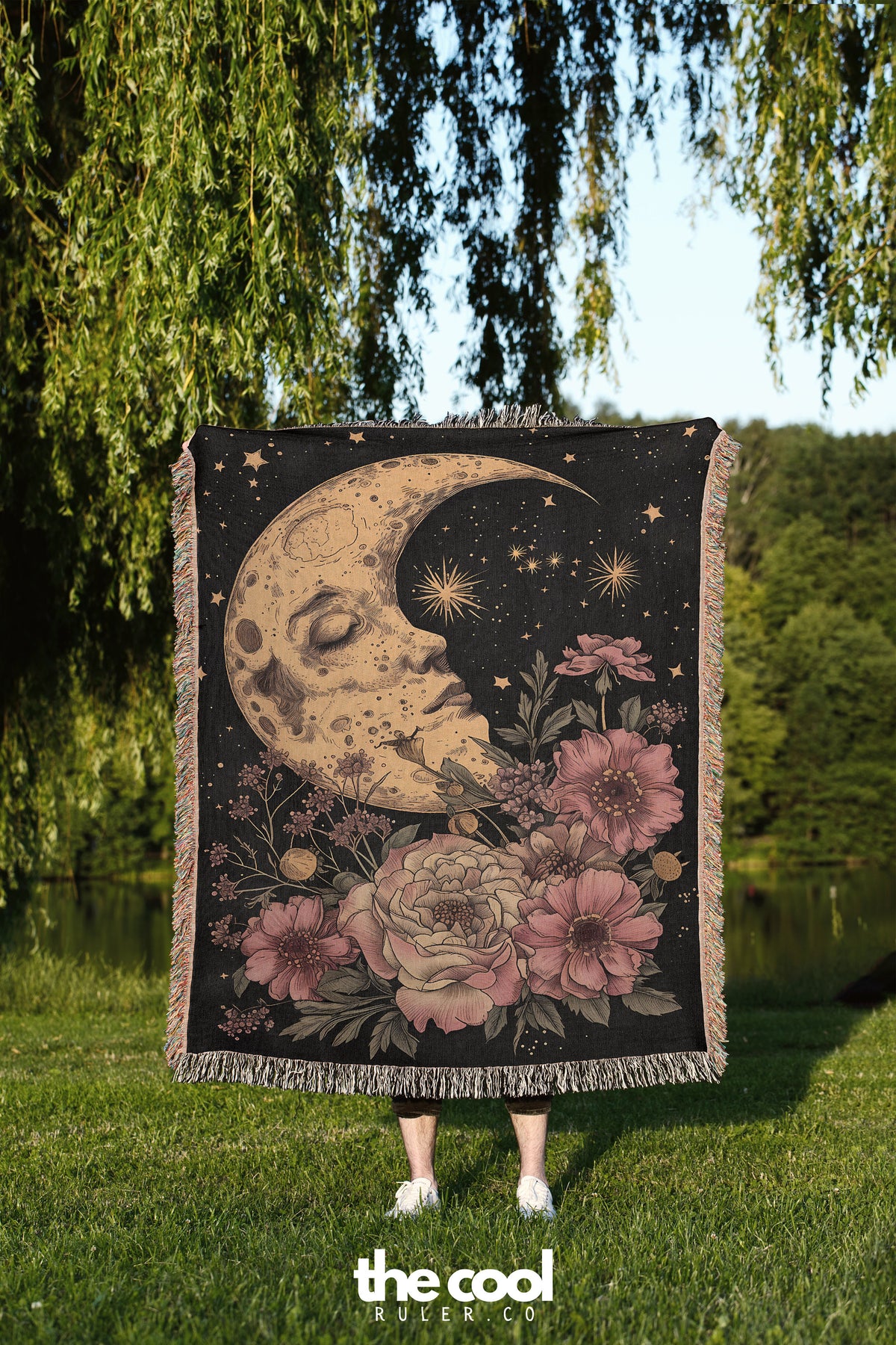 a woman standing in the grass holding a tapestry