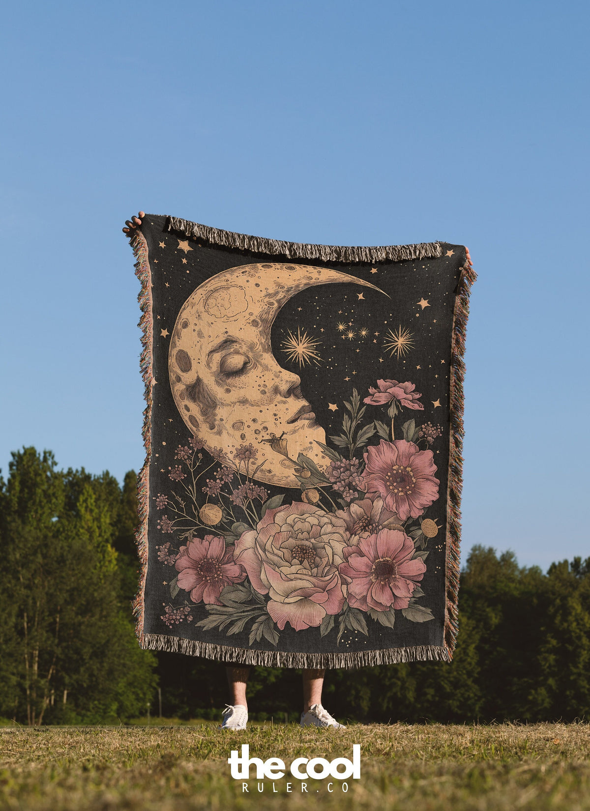 a woman standing in a field holding a tapestry