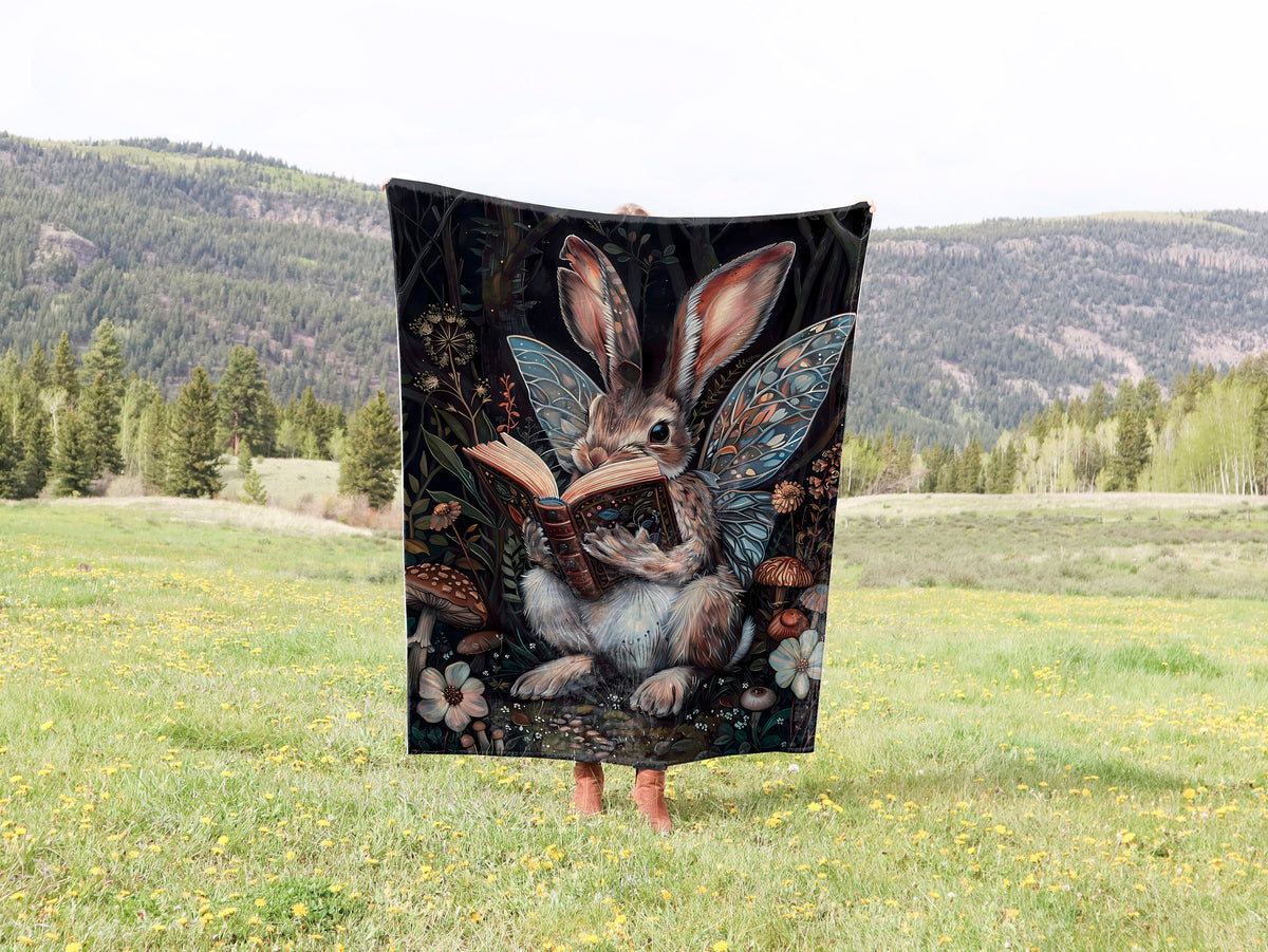 a blanket with a picture of a bunny reading a book