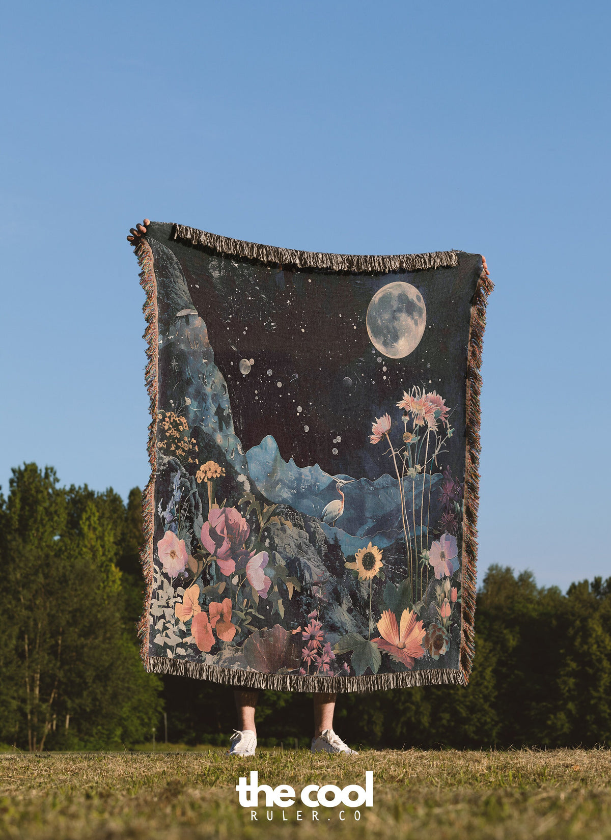 a woman standing in a field holding a large tapestry