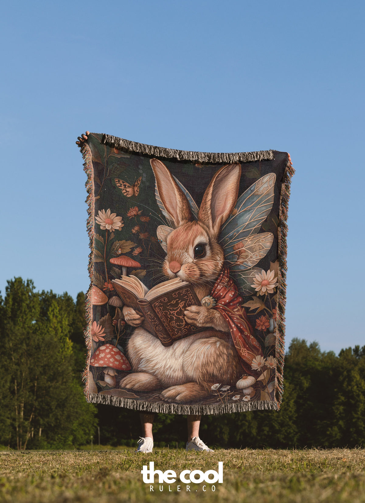 a woman standing in a field holding a blanket with a picture of a bunny reading