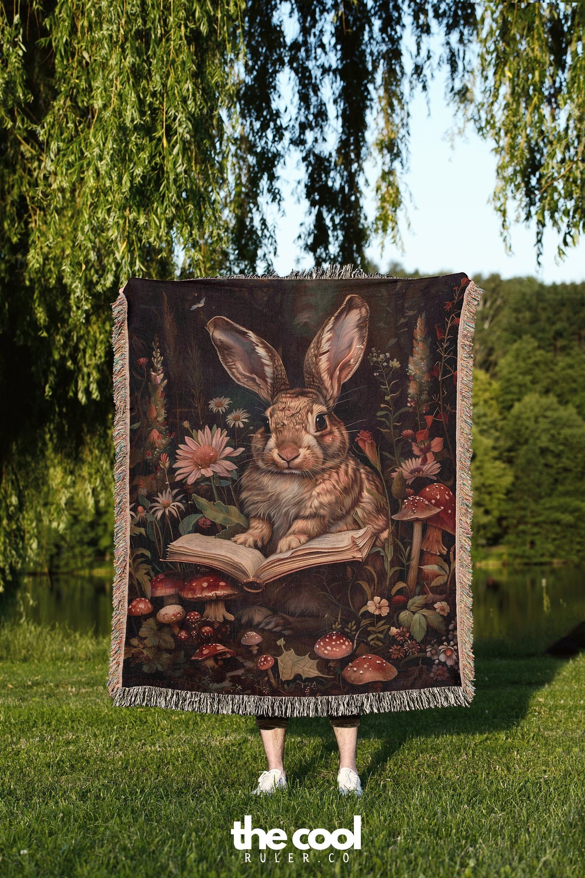 a blanket with a painting of a rabbit reading a book