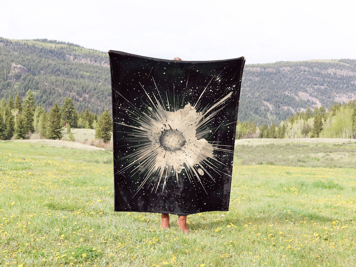 a person standing in a field holding a black and white blanket