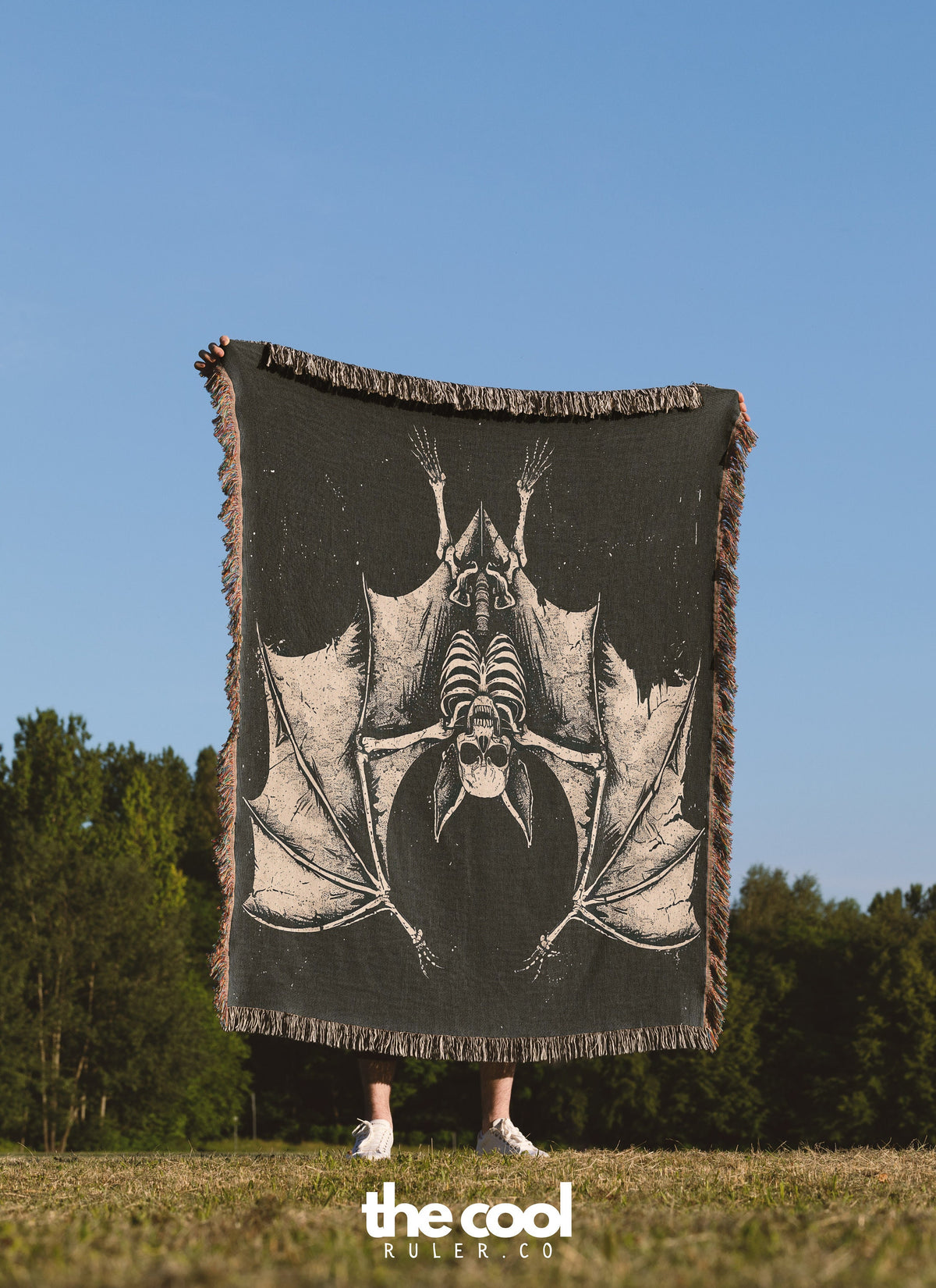 a person standing in a field holding a black and white bat blanket