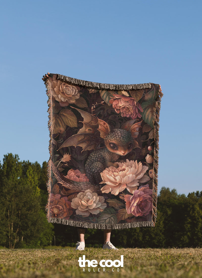 a woman standing in a field holding a blanket with flowers on it