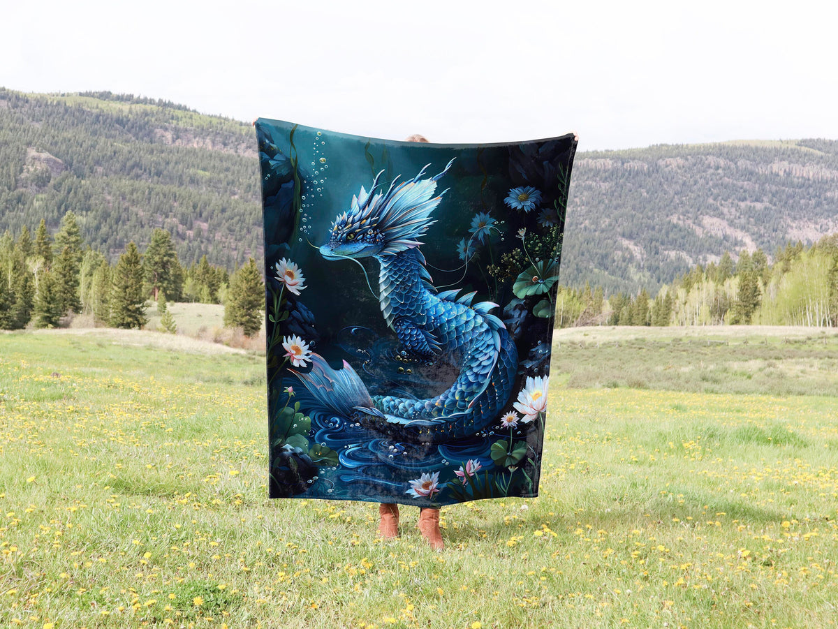 a woman standing in a field holding a blue dragon blanket