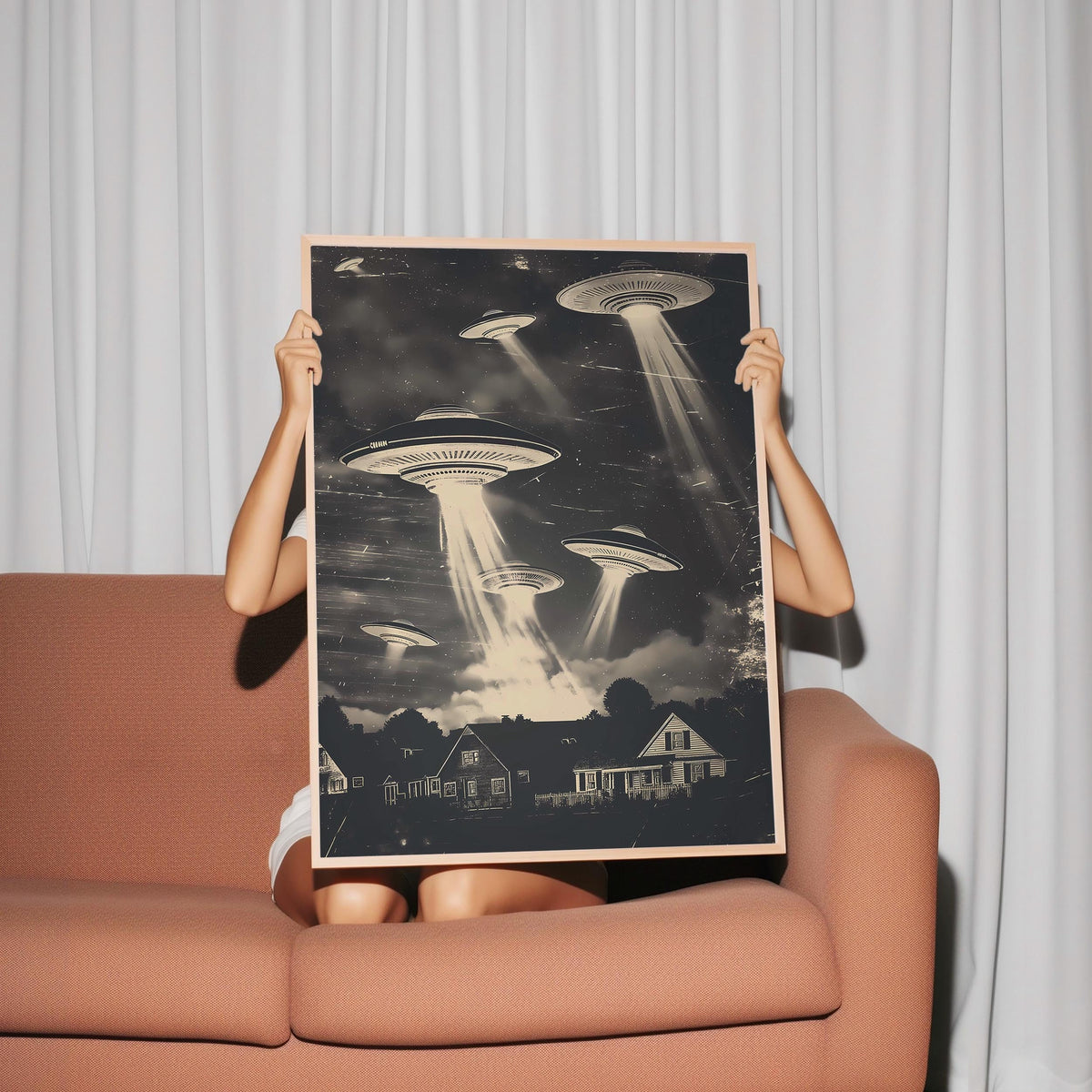 a woman sitting on a couch holding up a poster