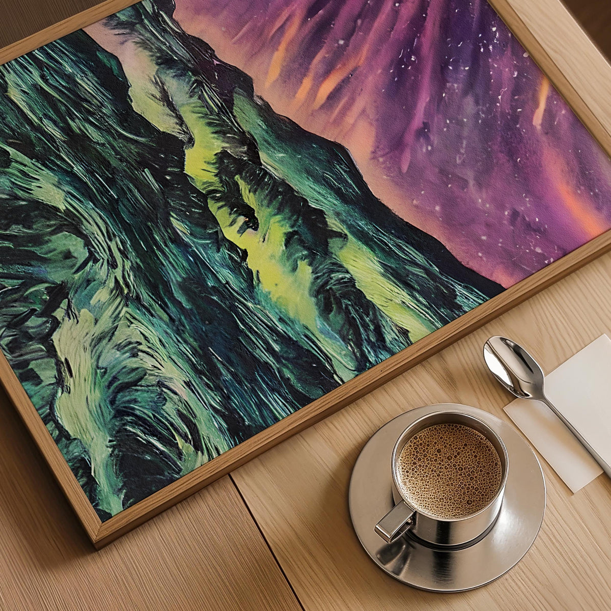a cup of coffee next to a painting on a table